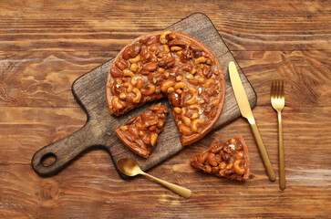 Wall Mural - board of cut sweet tart with different nuts and caramel on wooden background