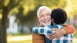 © alphaonetwo - Cherished Embrace: An older man and a younger person share a heartfelt embrace under the soft, natural light of a tranquil park. A picture of love, warmth, and connection