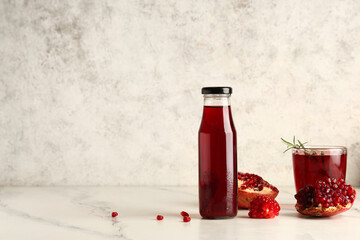 Wall Mural - bottle and glass of fresh pomegranate juice with rosemary on white background