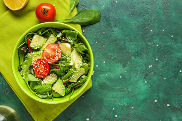 Wall Mural - Bowl of tasty avocado salad with cherry tomatoes and sesame seeds on green background