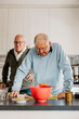© Johnér - Senior man leaning on counter while cooking in kitchen
