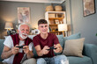 © Migma_Agency - Grandfather and grandson playing videogames on the sofa at home