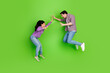 © deagreez - Young couple playfully interacting in casual outfits against a vibrant green background, showcasing joy, connection