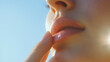 © TiA - Woman touching lips gently in sunlight close-up against blue sky