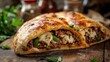 © Daphne - Cheesy beef and pepper stuffed calzone with herbs on rustic wooden table