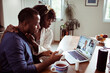© Marko Geber - Worried young african american couple talking to their doctor over a video call on their laptop in the kitchen while holding pills and perscription medicine