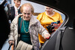© Alvaro Lavin/Stocksy - Caregivers helping elderly woman getting into car