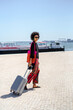 © tessy morelli/Stocksy - Lisbon Cais do Sodre traveler walking with suitcase