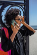 © tessy morelli/Stocksy - Sophisticated black woman outdoor portrait on phone call
