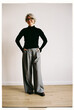 © Viktor Solomin/Stocksy - Fashionable woman in wide-leg trousers and black turtleneck