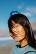 © Adrian Rodd/Stocksy - Portrait of Asian lady peacefully posing at the beach with eyes closed