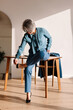 © Viktor Solomin/Stocksy - Woman adjusting high heel shoe while sitting at stylish wooden table