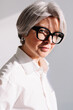 © Viktor Solomin/Stocksy - Stylish older woman with grey hair and glasses posing in bright room