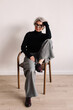 © Viktor Solomin/Stocksy - Confident woman in modern outfit sitting on chair