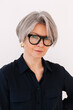 © Viktor Solomin/Stocksy - Professional woman with gray hair and stylish glasses