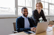 © BONNINSTUDIO/Stocksy - Formal business colleagues collaborating on laptop in modern office
