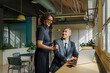 © BONNINSTUDIO/Stocksy - Formal business colleagues collaborating on laptop in modern office