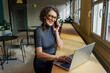 © BONNINSTUDIO/Stocksy - Formal businesswoman working on laptop and talking on phone in office