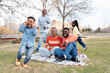 © Santi Nuñez/Stocksy - Happy family enjoying picnic in park with children playing
