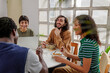 © BONNINSTUDIO/Stocksy - Happy colleagues enjoying lunch break together in workspace