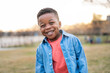 © Santi Nuñez/Stocksy - Portrait of happy african american child smiling outdoors in a park