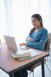 © Charlie's - Pregnant asian woman using laptop at home pregnant businesswoman typing on laptop working on remote project in home office pregnancy concept