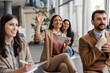 © Dusan Petkovic - Young professional businesswoman sitting at training room with her colleagues and holding her hand raised.