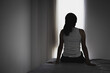 © Tinnakorn - Silhouette of Young women sitting in dark room feeling pain with life problem. suffering from husband violence, Stop violence against and sexual abuse women, domestic violence, anti human trafficking.