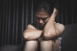 © Tinnakorn - A depressed young woman sits sadly on a sofa, covering her face with her hands. Depressing atmosphere. Relationship problems. Violence against women.