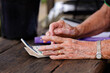 © Austockphoto - Senior woman’s hands adding up purchase amount at counter of nursery garden small business