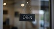 © Joa - Black rectangular 'OPEN' sign hanging on a glass door by two small chains.