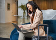 © Meeko Media - Businesswoman on a Call and Laptop in a Modern Hotel Lobby Setting