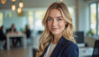 © f_bossa - A portrait headshot photo of a friendly professional CEO executive business worker: A young professional woman with blonde hair and blue eyes confidently smiles at the camera while wearing a navy