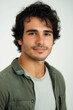 © Wilker - A close-up headshot of a young man with dark, curly hair and olive skin. He has a short, well-groomed beard and mustache.  His expression is neutral, bordering on a slight smile, conveying calmness