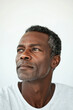 © Wilker - Close-up portrait of a middle-aged man with dark skin and graying hair. The image is sharply focused on his face, showcasing detailed texture of his skin. His gaze is directed upward and slightly to