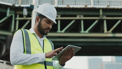 Portrait of thoughtful architect designer working on tablet computer standing near bridge. Inspired man engineer uses portable computer to control at construction site. Copy space