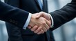 © abu - Close Up of Two Men in Dark Suits Handshaking in a Professional Office Setting