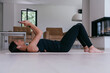 © .shock - A sportswoman using a smartphone while resting and lying on the modern house floor