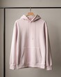 © stock.finder - Pale pink hoodie hanging on a wooden hanger against a neutral background. Minimalist fashion and streetwear concept