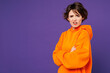 © ViDi Studio - Side view young sad frowning mad indignant suspicious woman she wearing orange hoody casual clothes holding hands crossed folded isolated on plain purple background studio portrait. Lifestyle concept.
