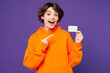 © ViDi Studio - Young shocked surprised happy woman she wear orange hoody casual clothes hold in hand point index finger on mock up of credit bank card isolated on plain purple background studio. Lifestyle concept.