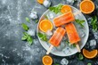 © Velar - Orange juice ice lollies on sticks, captured from above in a flat lay arrangement, showcasing their vibrant color and texture