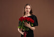 © New Africa - Smiling woman with bouquet of roses on brown background