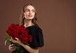 © New Africa - Smiling woman with bouquet of roses on brown background. Space for text