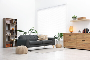 Poster - Stylish living room with comfortable sofa and wooden shelving unit. Interior design