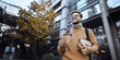 © BARLOP - Smiling Young Man Walking Outdoors with Coffee and Backpack in Urban Scene.