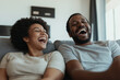 © sam richter - African American couple laughing together on couch