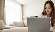 © Nina - A Young Caucasian Woman Engaged in Remote Work on a Laptop in a Bright, Cozy Living Room with Natural Light Streaming Through Windows