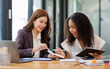 © David - Two business women or an accountant team are analyzing data charts, graphs, and a dashboard on a laptop screen in order to prepare a statistical report and discuss financial data in an office