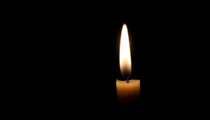 Wall Mural - lit candle in the dark with a black background